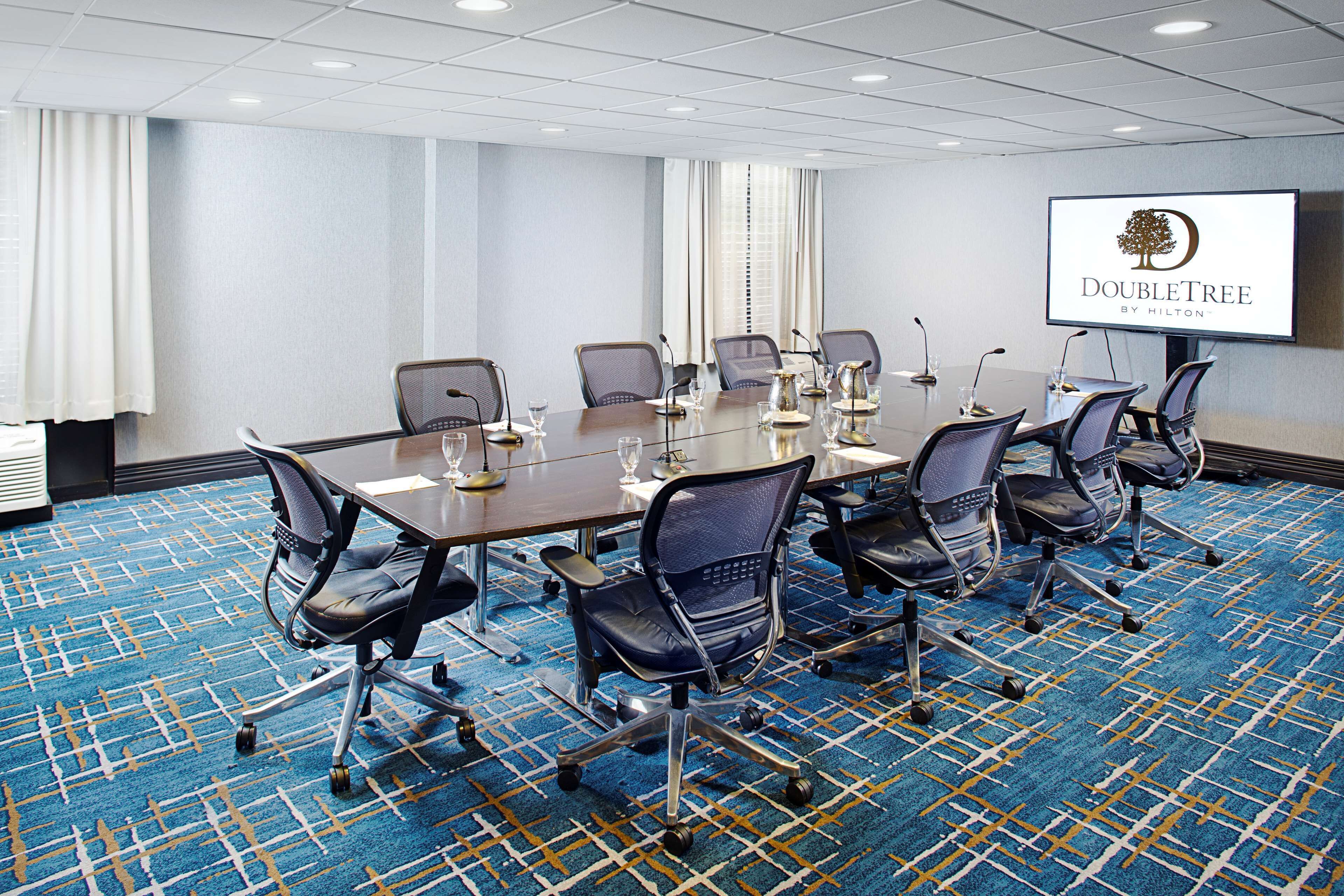 A conference room with a long table, multiple chairs, and a screen displaying the DoubleTree logo.