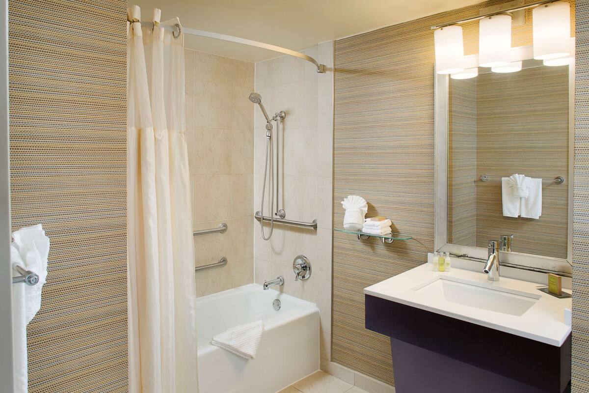 A modern bathroom with a bathtub, shower, and vanity.