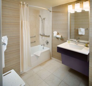 A modern bathroom with a bathtub, shower, and vanity.
