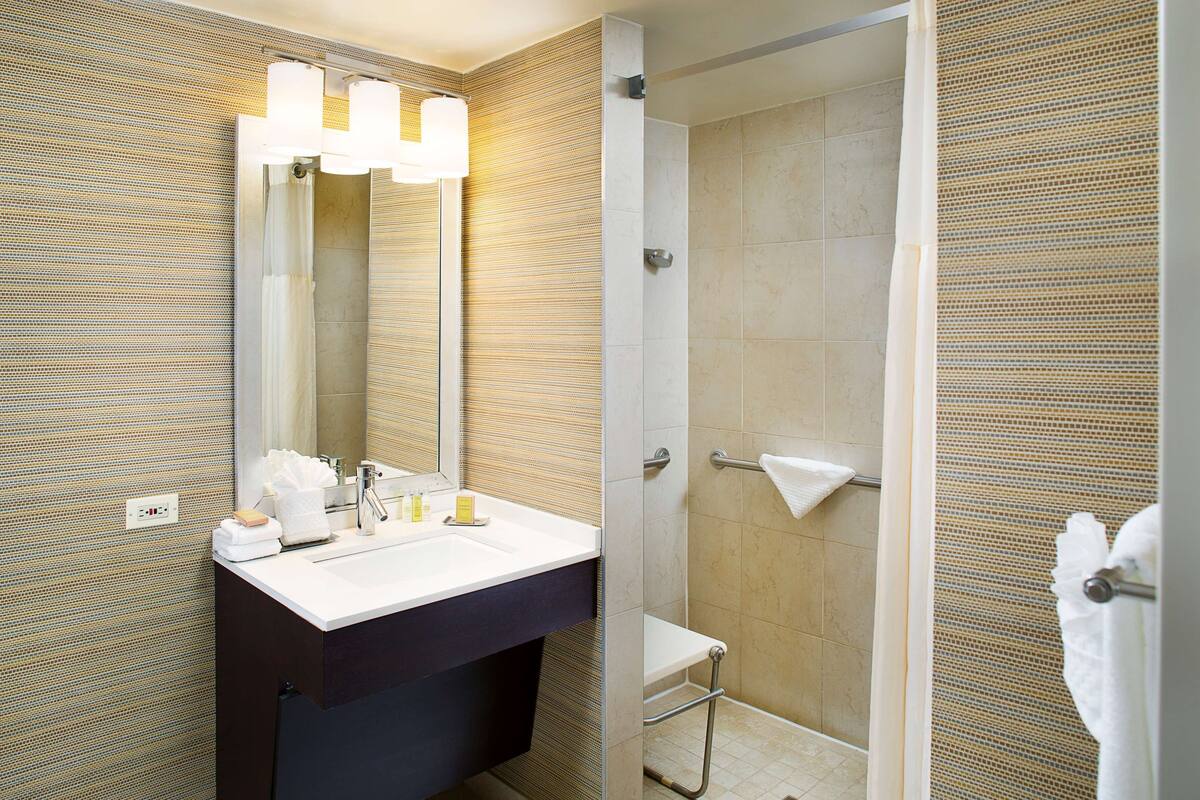 A modern bathroom with a large mirror, a sink, and a shower area.