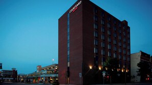 A Courtyard hotel with a brick facade, multiple floors, and a prominent sign at the top. - Courtyard St. Cloud (St Cloud)