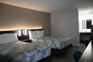 Una habitación de hotel con dos camas, un escritorio y un espejo.