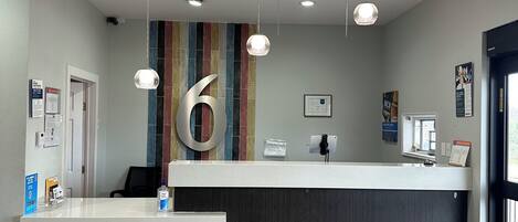 A modern reception area with a large number '6' on the wall, a reception desk, and a patterned floor.