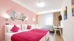 Une chambre d’hôtel comprenant un lit, deux tables de chevet, un bureau, une chaise, un téléviseur et un élément décoratif mural.