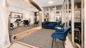Un hall d’hôtel comprenant un comptoir d’accueil, un espace salon et une vue sur la rue.