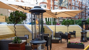 An outdoor patio area with wicker furniture, planters, and a decorative metal lantern. - Copthorne Tara Hotel London Kensington (London)