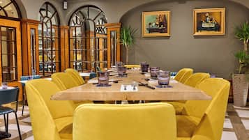 Comedor con una mesa larga, sillas amarillas y copas de vidrio morado.
