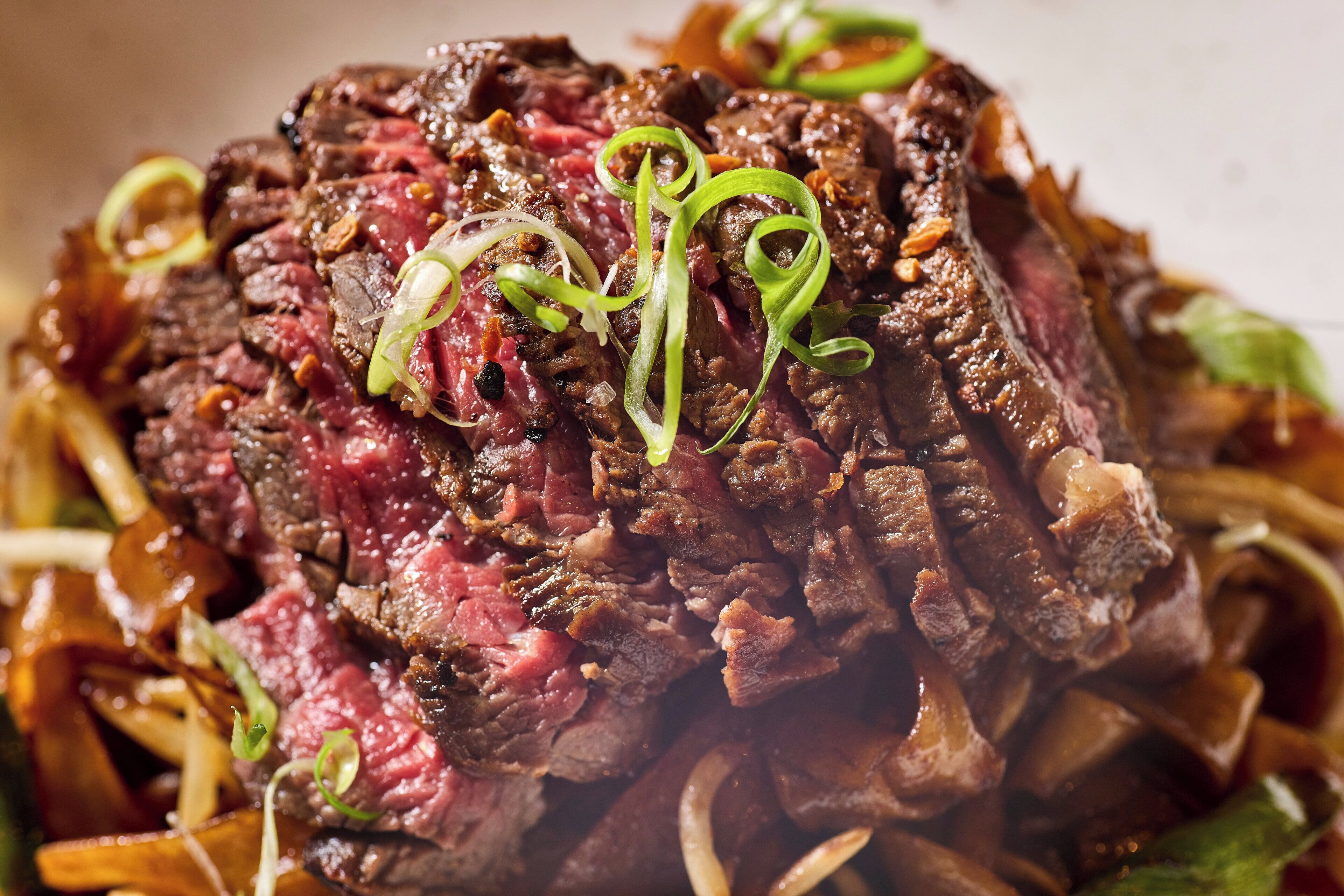 A close-up of a cooked steak with green garnish.