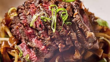 A close-up of a cooked steak with green garnish.