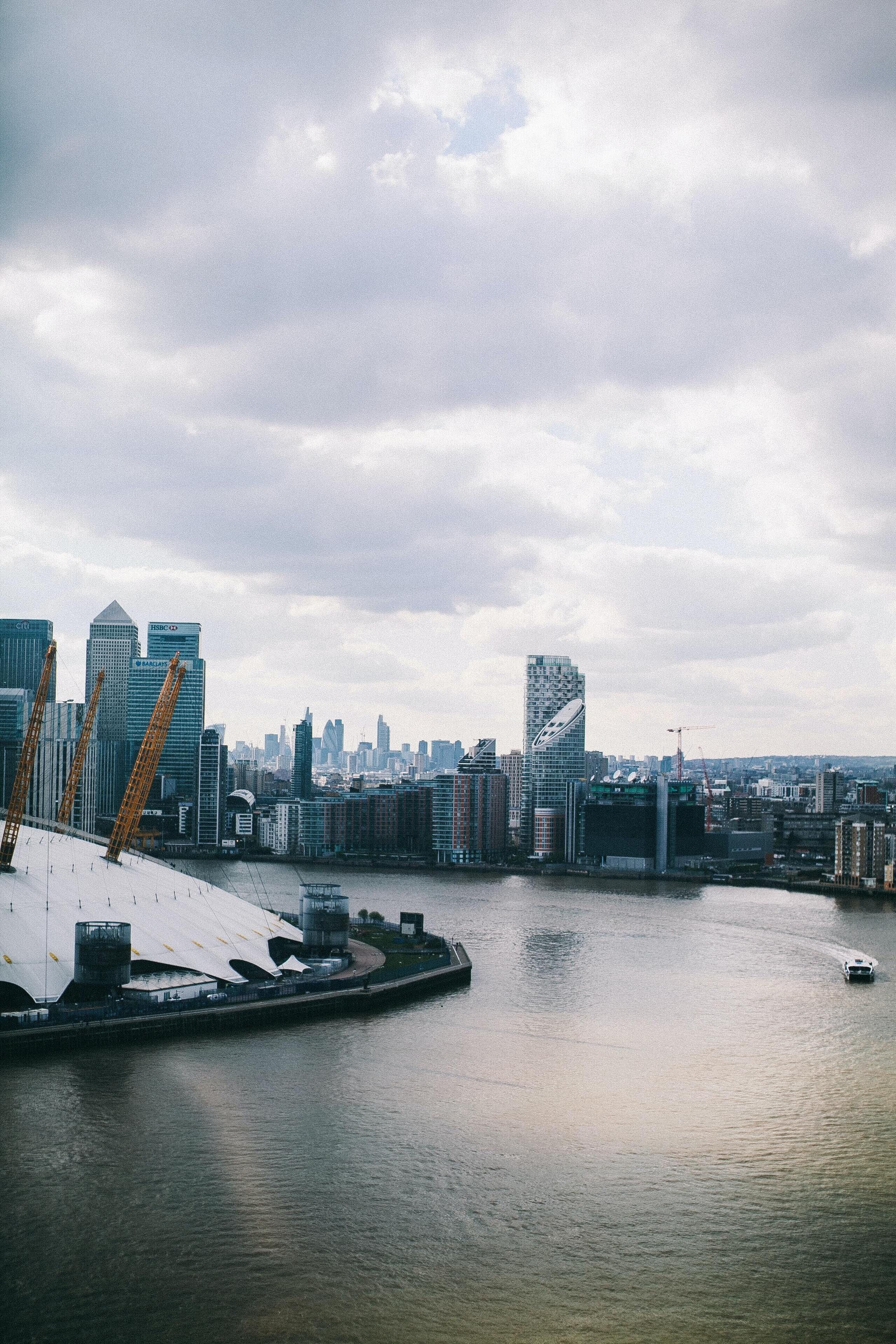 A city skyline with modern buildings, a waterfront, and a bridge.
