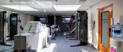 Un gimnasio moderno con equipo de ejercicio, una zona de recepción y un dispensador de agua grande.