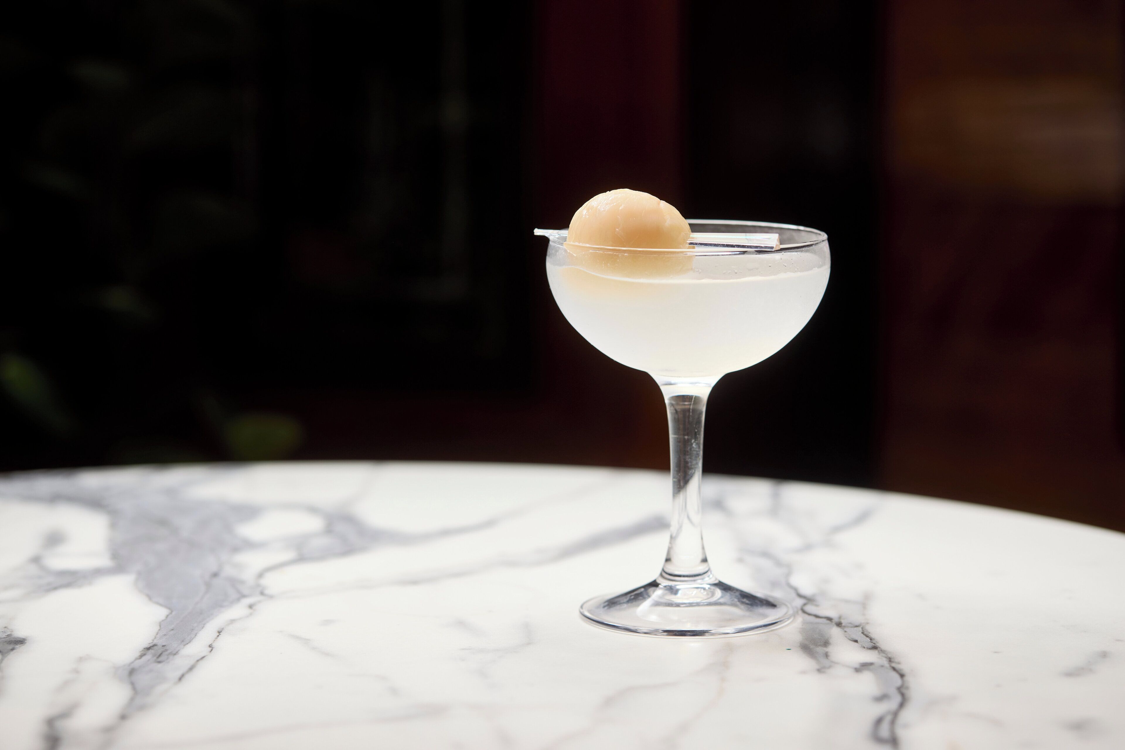 Un got de martini amb una guarnició esfèrica sobre una taula de marbre.