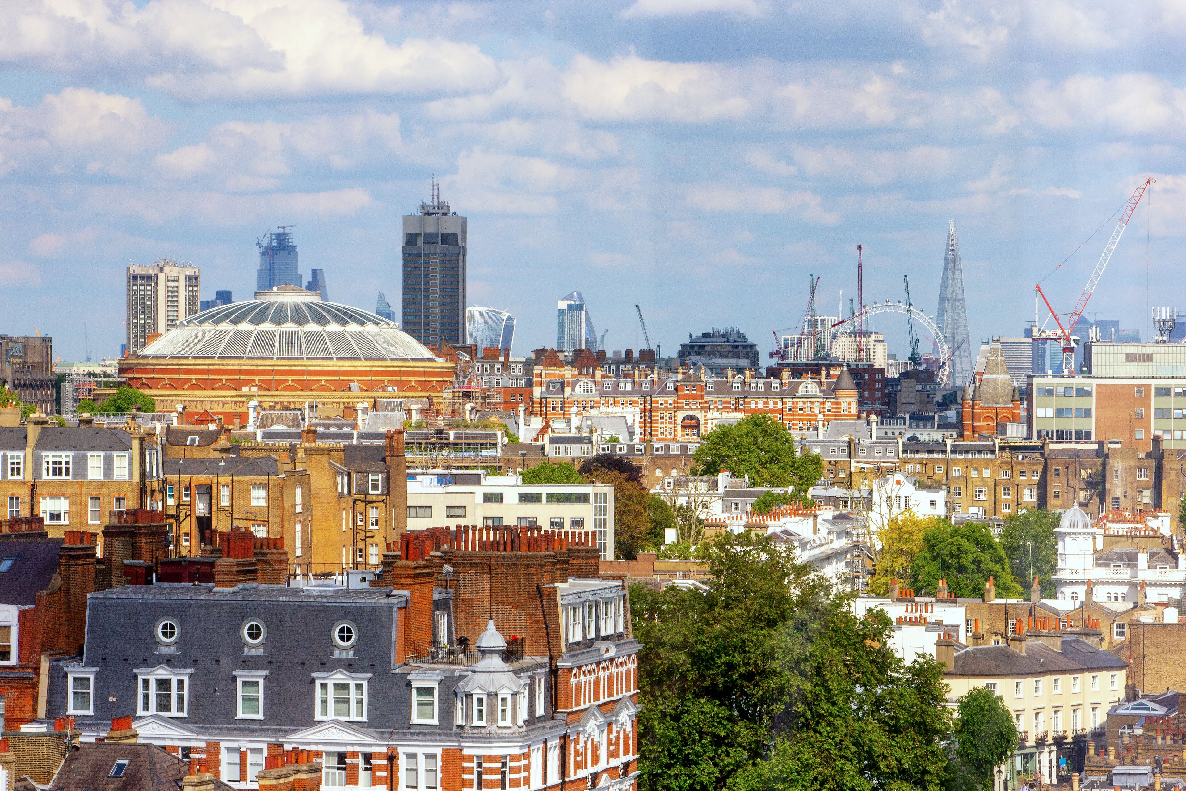 Un paisaje urbano con una mezcla de edificios históricos y modernos, incluyendo una cúpula destacada y el London Eye.
