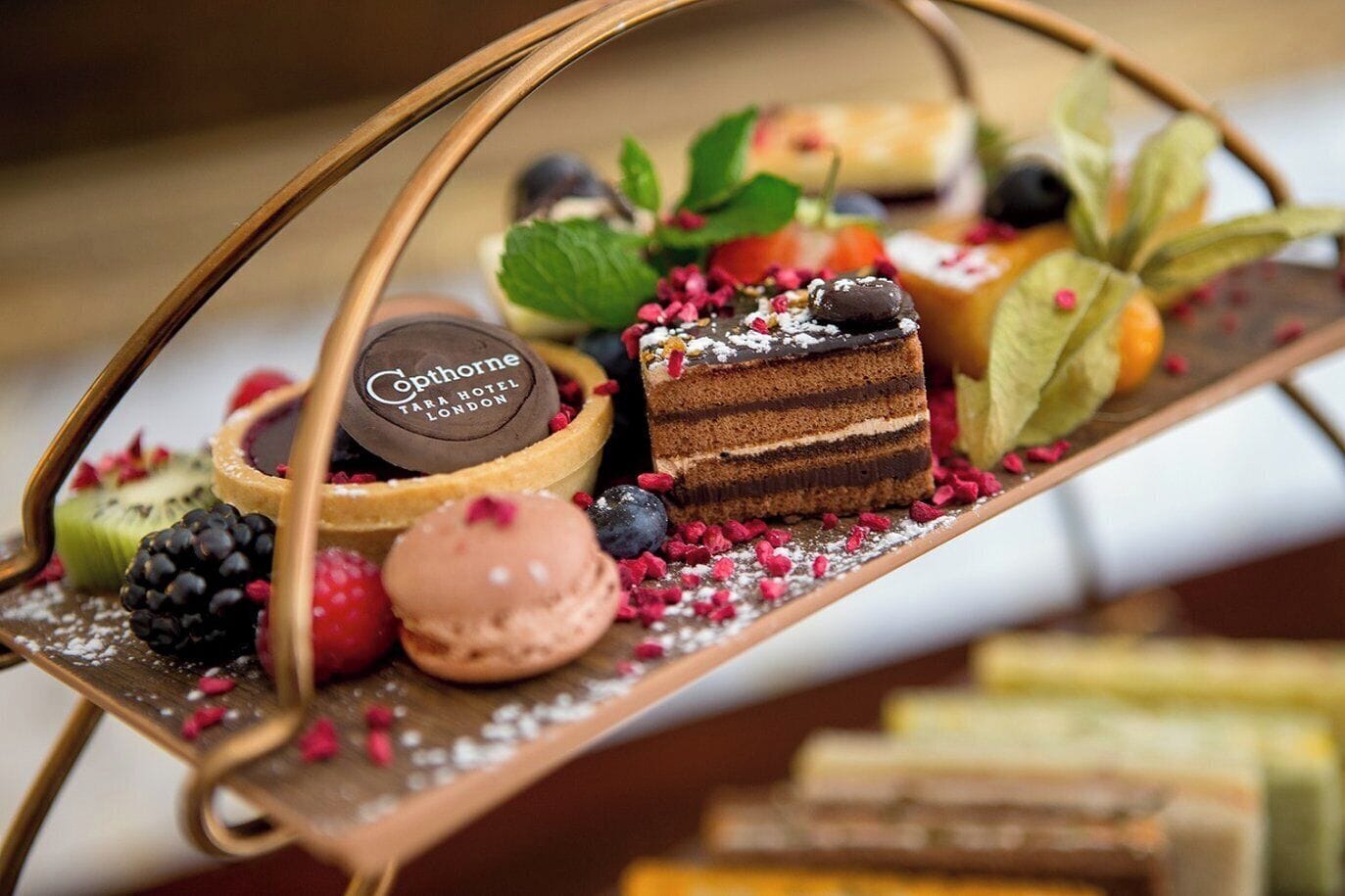 A dessert tray with various sweets and a sign that reads "Cophorne Tara Hotel London".