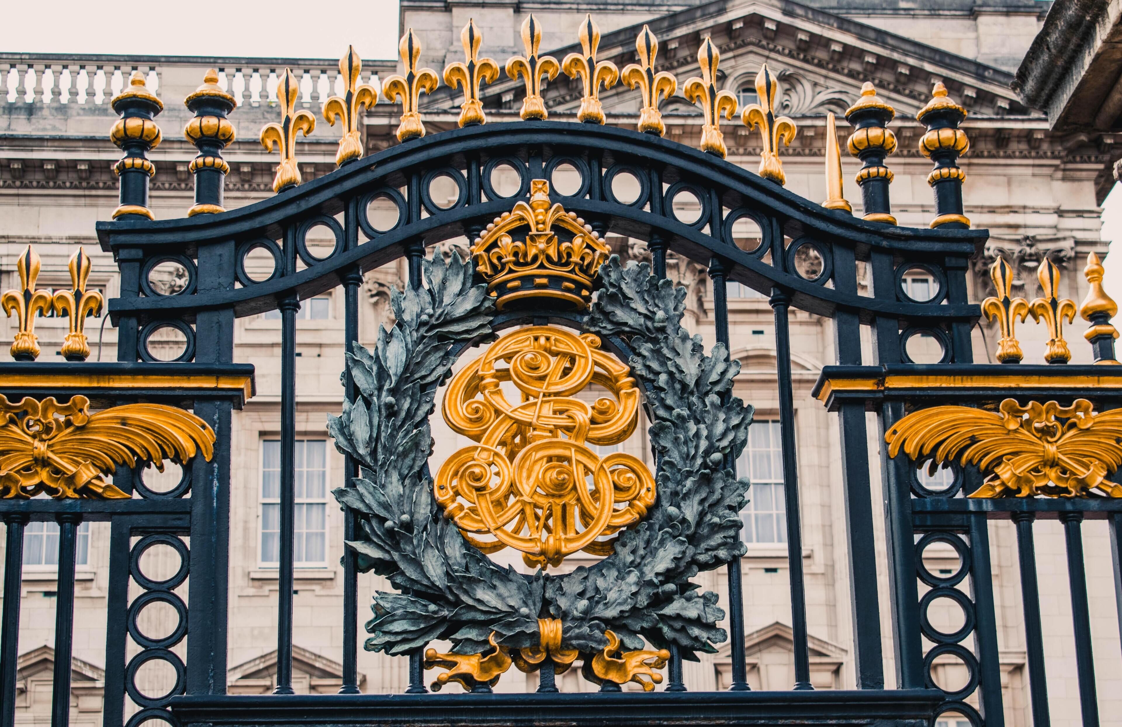 Een zwart ijzeren hekwerk met gouden accenten en een familiewapen.