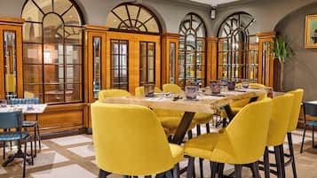 Un comedor con mesa de madera, sillas amarillas y ventanas arqueadas amplias.