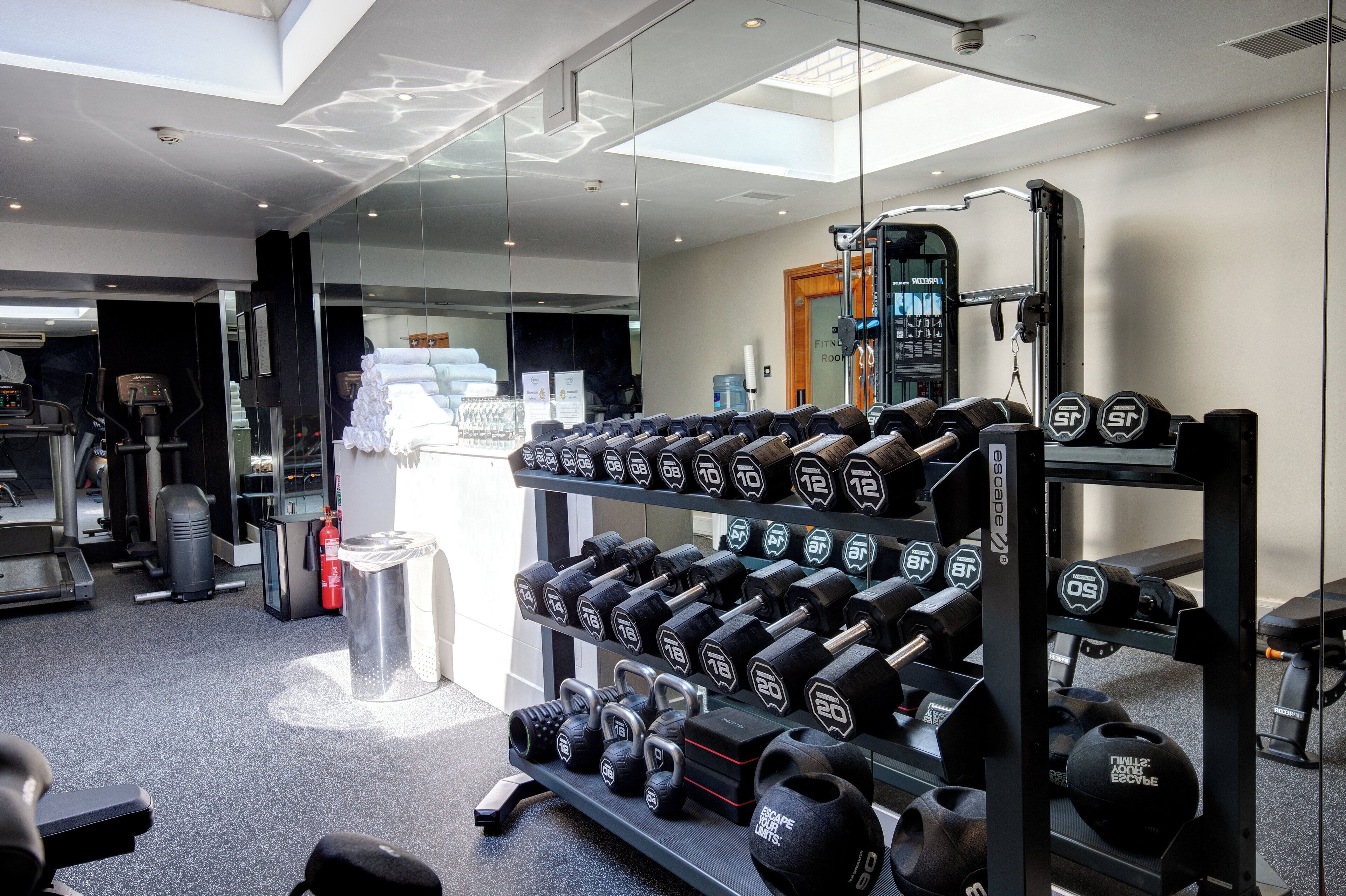 A gym with weightlifting equipment, including dumbbells and kettlebells, and a treadmill.