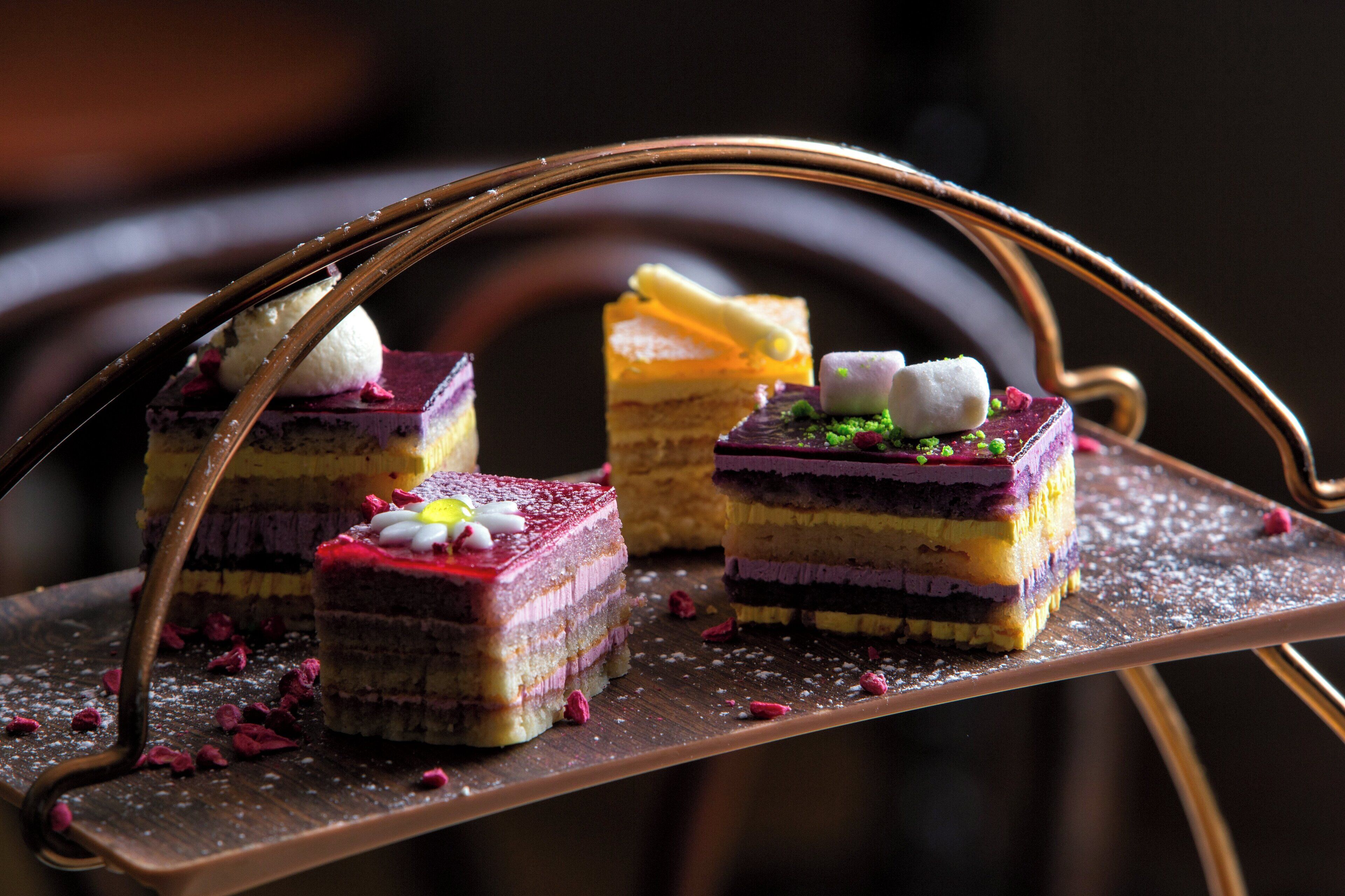 A dessert tray with multiple layered cakes and a metal serving stand.