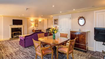 A dining area with a wooden table and chairs, a fireplace, a sofa, and a television.