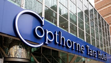 The exterior of the Opthorne Tara Hotel with a modern glass facade and a prominent blue sign.