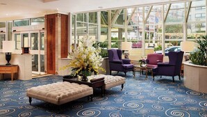 A hotel lobby with a large window, a blue patterned carpet, and purple armchairs. - Copthorne Tara Hotel London Kensington (London)