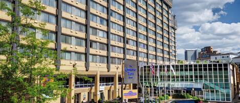 A hotel with a modern design, featuring a large glass facade and a sign indicating it is The Copthorne Tara Hotel.