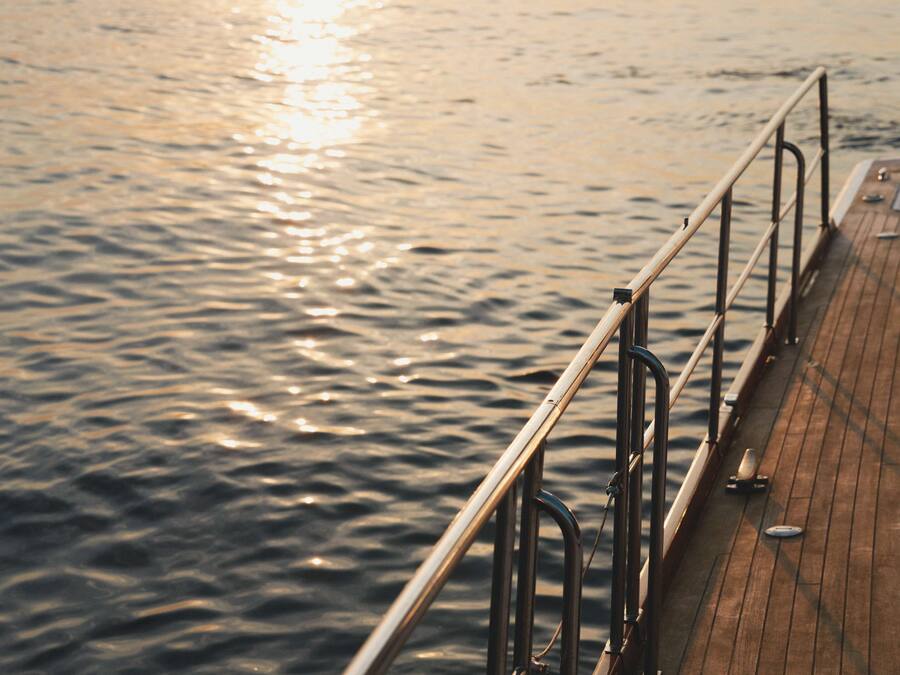 Un muelle de madera que se extiende sobre agua tranquila con barandilla de metal.