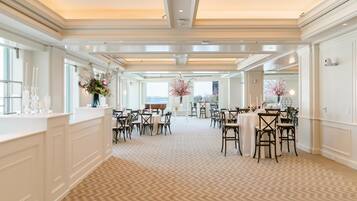Een ruime hotellobby met een kamerbreed tapijt, witte muren en kroonluchters.