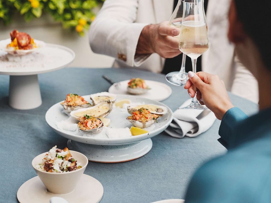 Une table à manger avec des assiettes remplies de nourriture et un verre de vin.