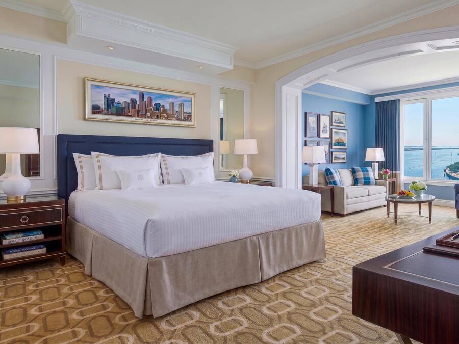 Habitación de hotel con una cama grande, un sofá, un escritorio y vistas a la ciudad.