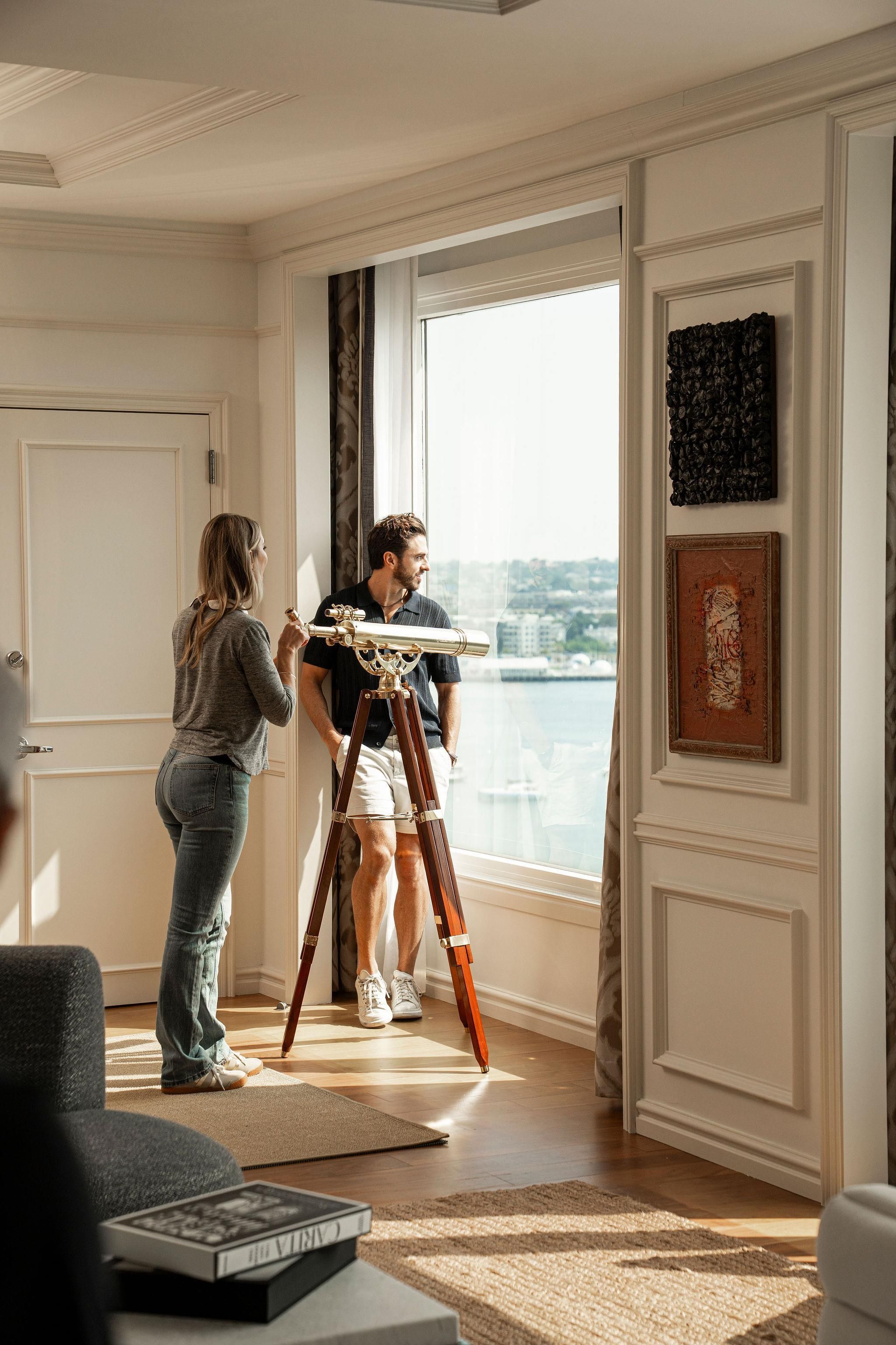 Ein Zimmer mit großem Fenster, einem Stativ und einer Person, die eine Kamera benutzt.