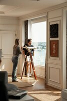 A room with a large window, a tripod, and a person using a camera.