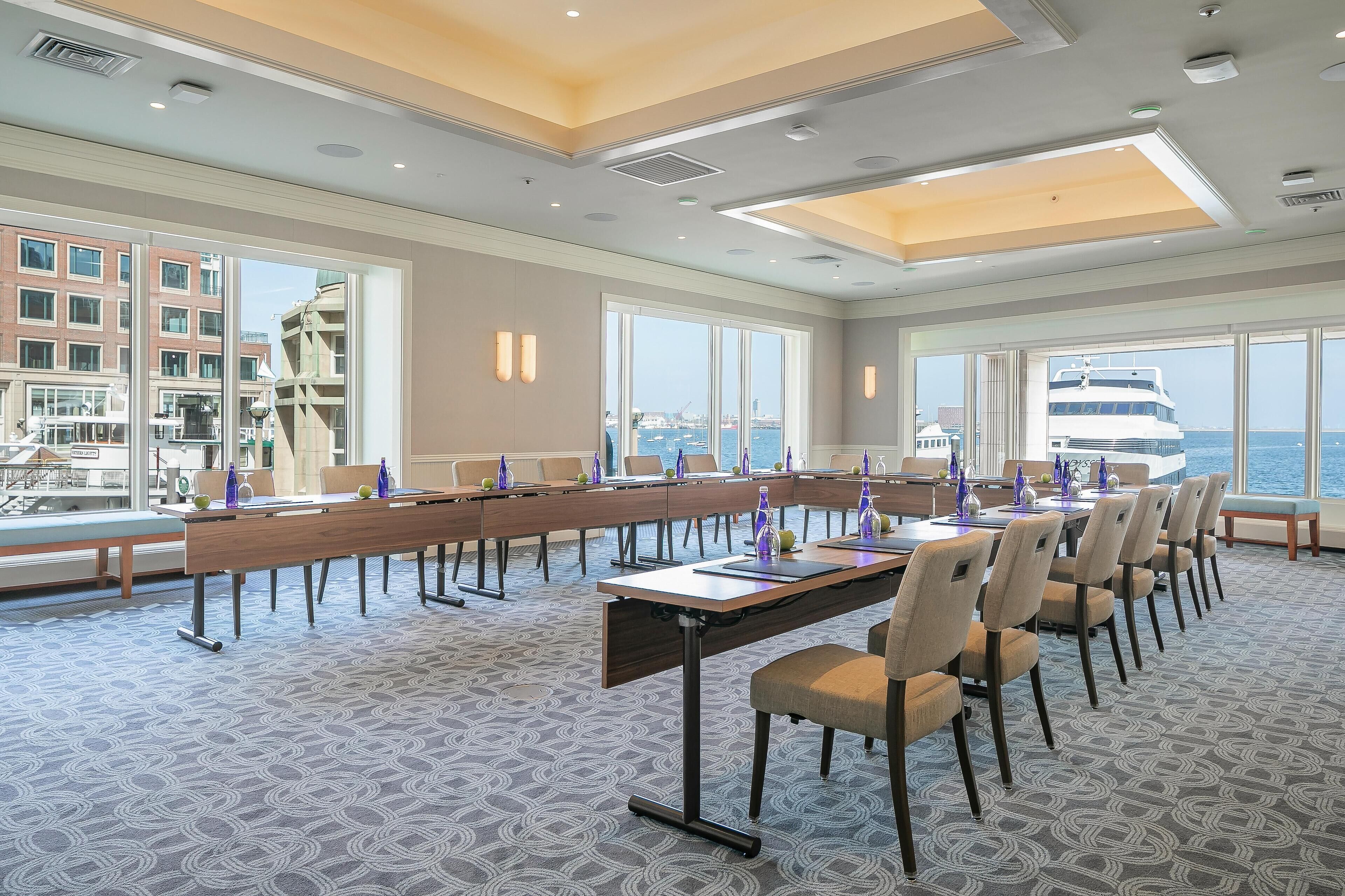 Une salle de conférence dotée d’une longue table, de chaises et de grandes fenêtres donnant sur une marina.