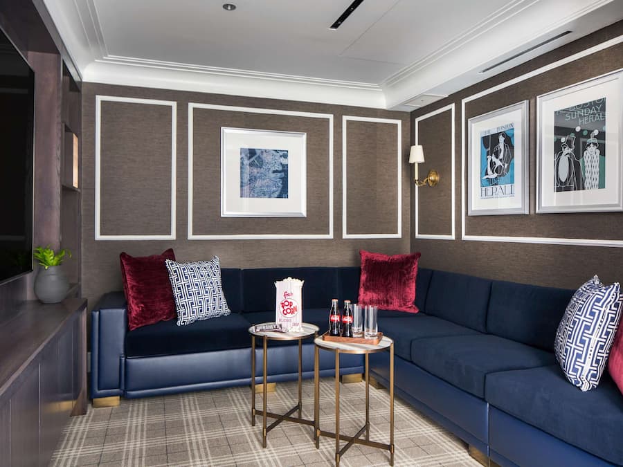 A modern living room with a dark blue sofa, red and patterned pillows, a popcorn machine, and framed artwork on the walls.