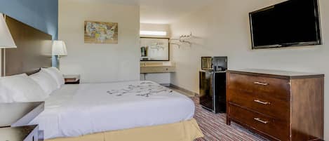 A hotel room with a bed, a dresser, a television, a desk, and a mirror.