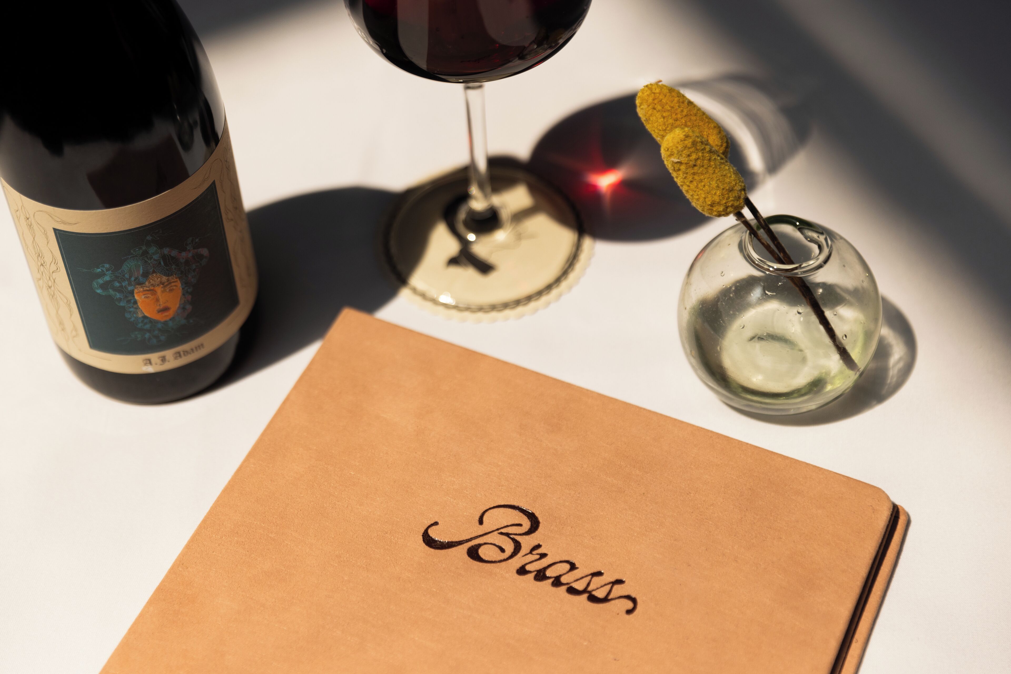 A bottle of wine, a wine glass, and a small glass with a yellow sponge.