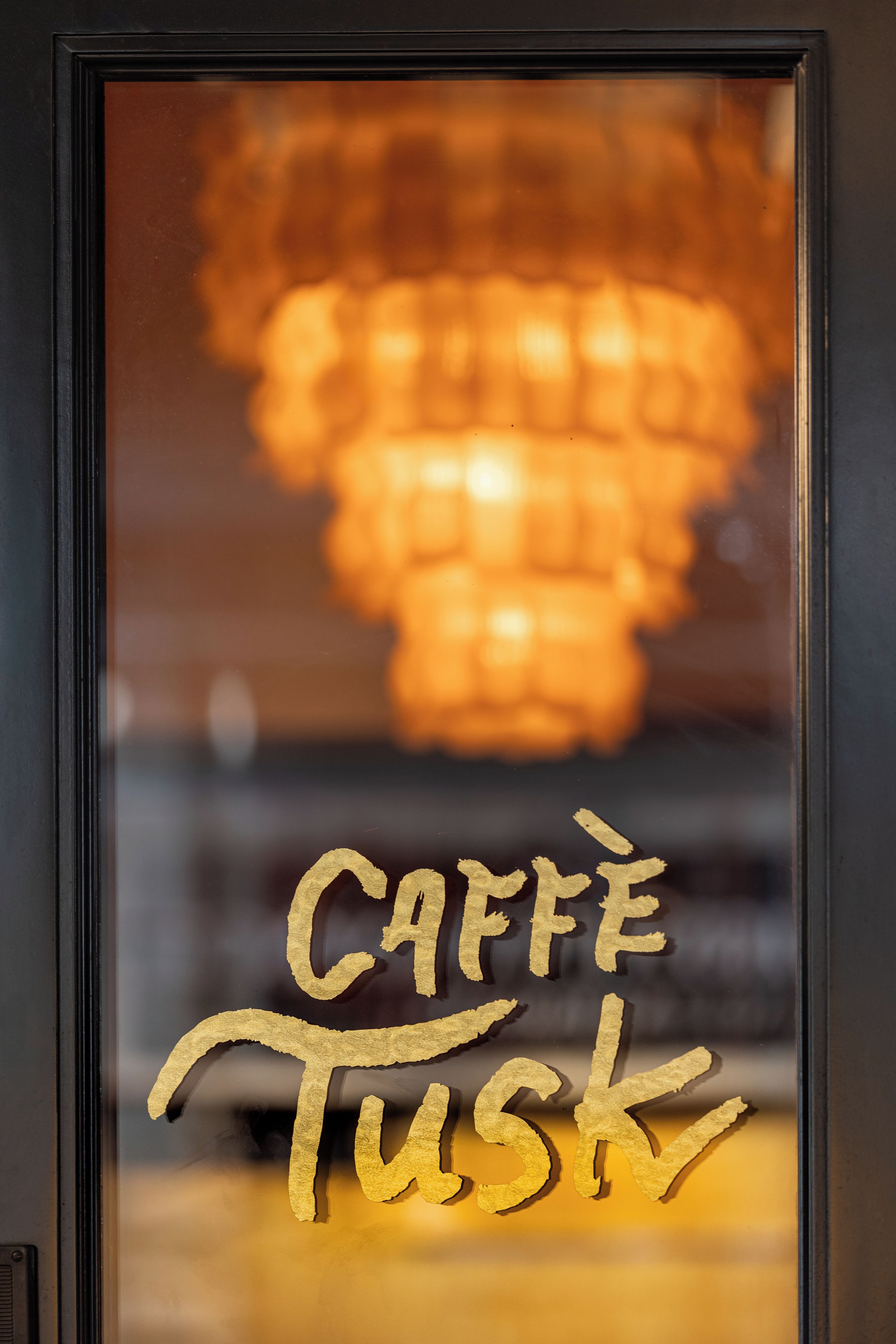 A framed sign with the words 'CAFFE TUSK' in gold lettering.
