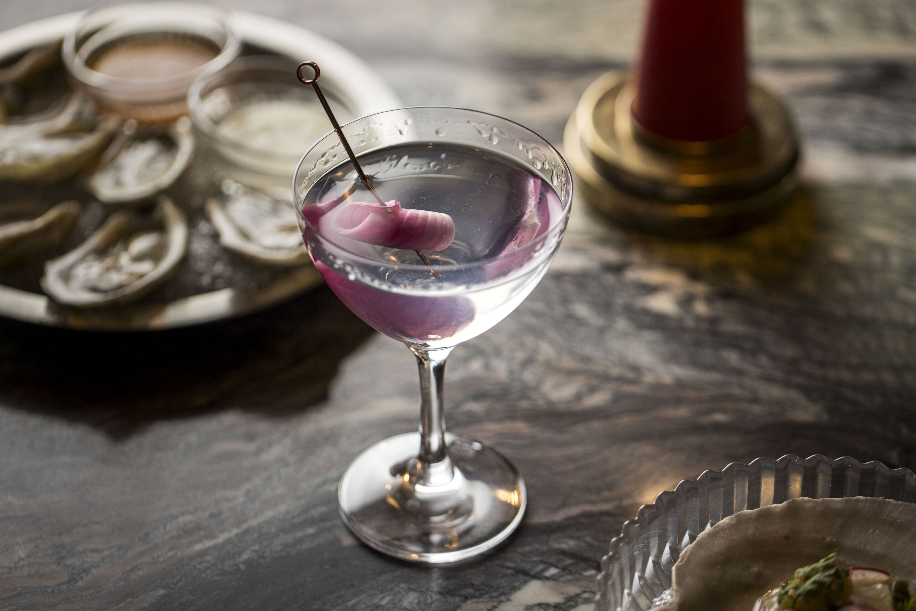 Un martini amb una cirera sobre una taula de marbre.