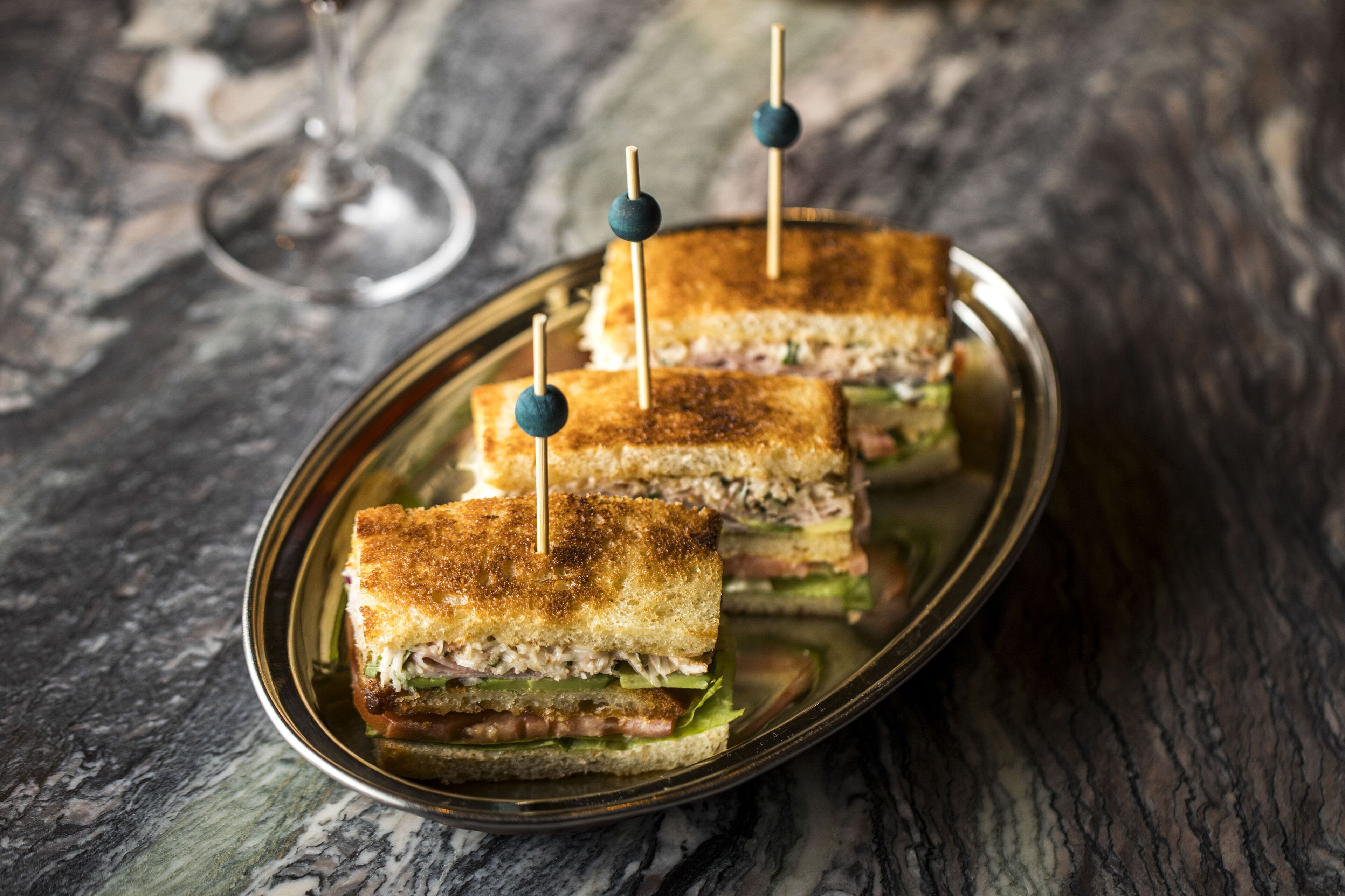 Un plato con tres sándwiches tostados, cada uno con un palillo.