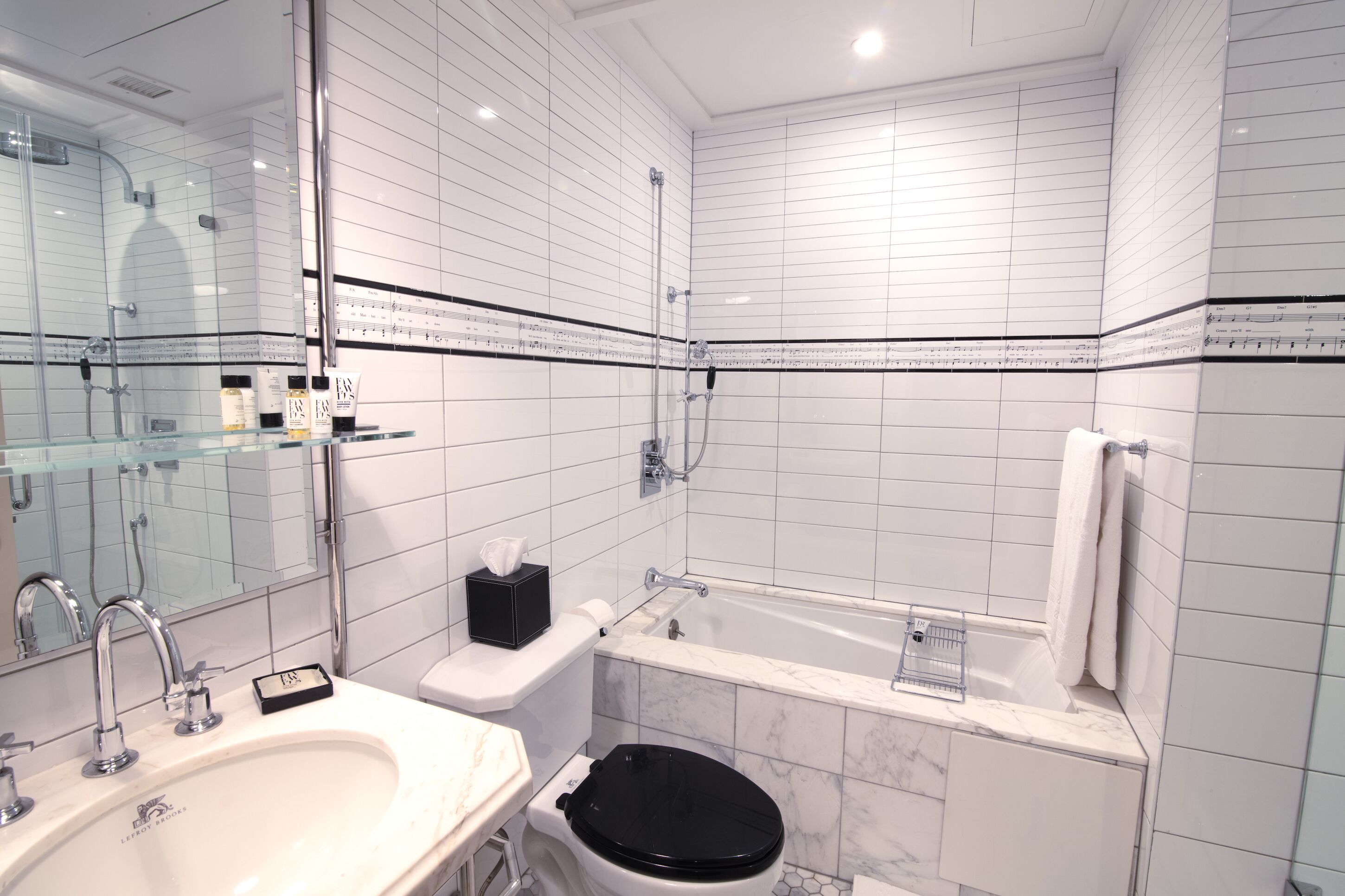Un baño moderno con lavamanos, inodoro y bañera blancos, todo con detalles de mármol.