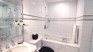 Un baño moderno con lavamanos, inodoro y bañera blancos, todo con detalles de mármol.
