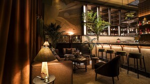 A bar area with seating, a bar counter, and a large window with a view. - The Evelyn Hotel (New York)