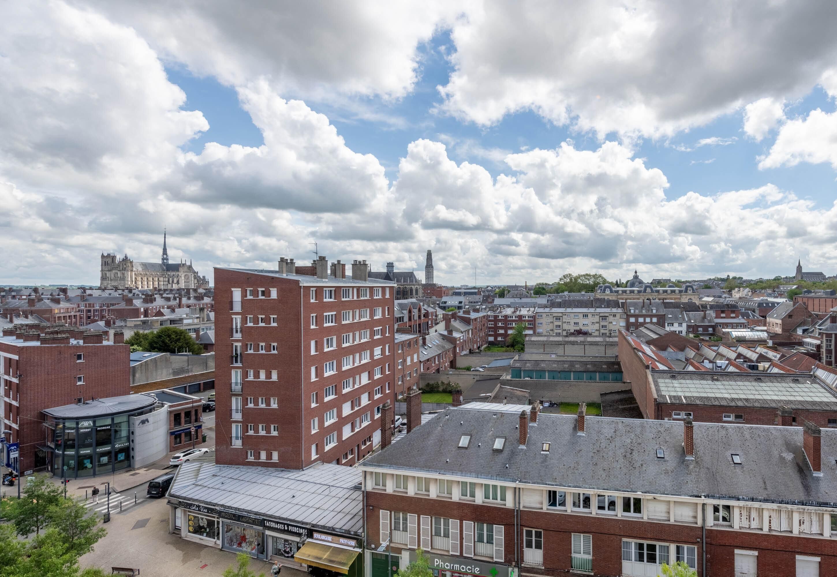 A cityscape with a prominent red-brick building, a church spire, and a mix of residential and commercial buildings.