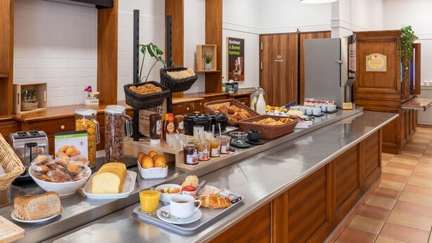 A buffet counter with various food items, a toaster, and a coffee station.