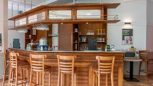 A bar area with wooden stools, a counter, and a microwave.