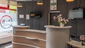 A reception desk with a laptop, a television, and a menu board.