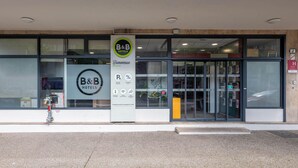 Entrada de un hotel B&B con puerta de vidrio, un cartel y señal de estacionamiento.