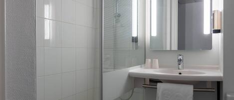 A modern bathroom with a glass shower enclosure, a white sink, and a mirror above it.
