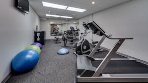 Un gimnasio con equipo de ejercicio, cintas de correr y pelotas de entrenamiento.