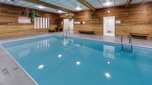 Una piscina interior con paredes de madera, bancos y señalización de seguridad.